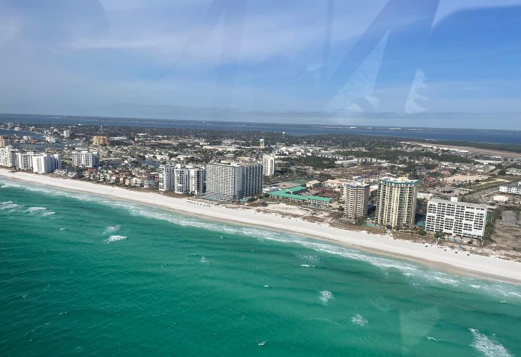 Aerial view of Destin, Florida beachfront condos and real estate properties along the white sand beaches and emerald green waters of the Gulf of Mexico.
