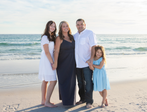 A smiling family of four on a Destin, Florida beach, representing a local Realtor that helps families find the perfect home.