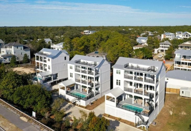 Aerial view of three modern luxury homes in Santa Rosa Beach, FL, each with a private pool and multiple balconies, representing prime 30A real estate.